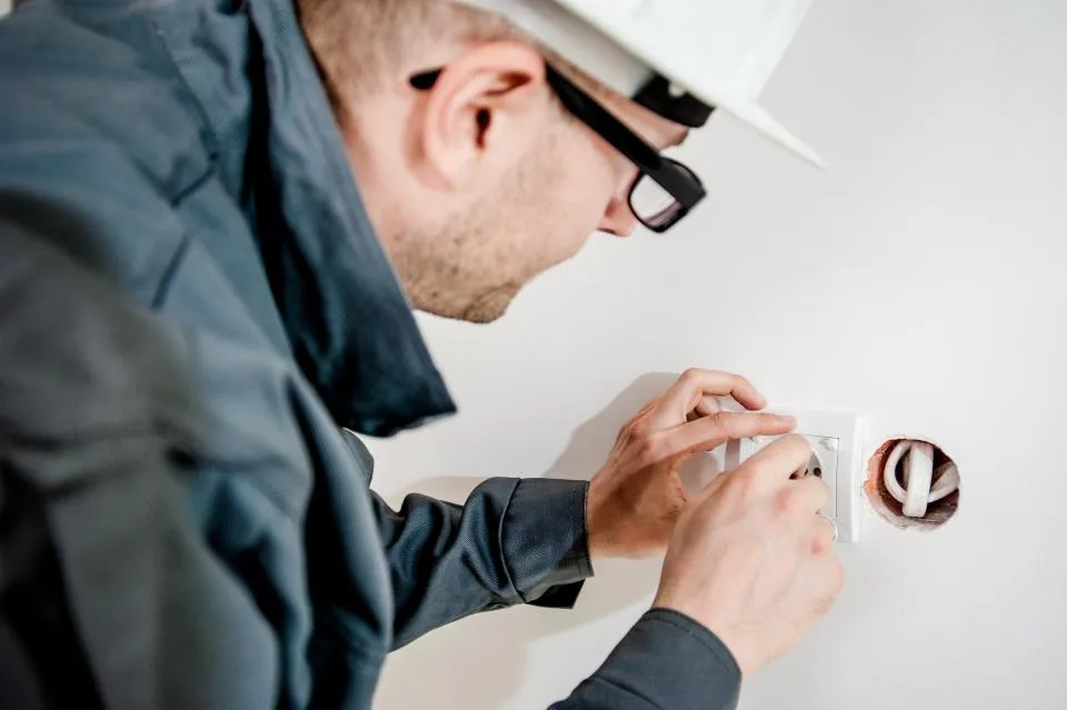 Electrician in safety glasses fitting a new wall outlet