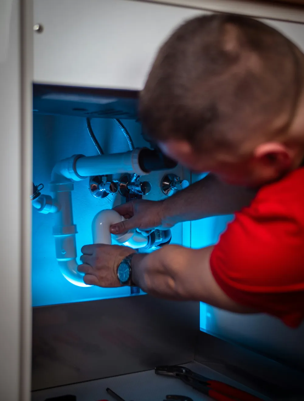 Plumber fixing the drain trap under a sink
